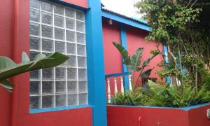 a red and blue building with windows and plants at Tri M Waves Lodge in Ponta do Ouro