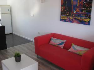 a red couch in a living room with a table at Hello Oliva Beach Alter in Oliva