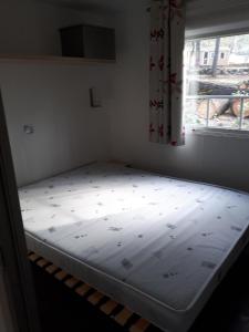 Bett in einem Zimmer mit Fenster in der Unterkunft Mobil Home Sainte Baume in Nans-les-Pins