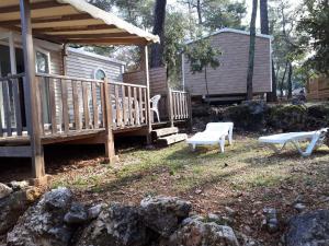 a cabin with a deck and a bench and a house at Mobil Home Sainte Baume in Nans-les-Pins