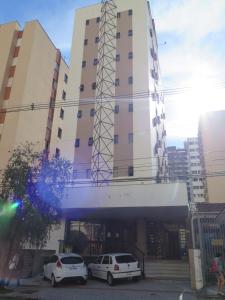 two cars parked in front of a tall building at Hotel Ideal in Londrina