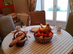 a table with a bowl of fruit and a basket of sausage at Gîte Mido in Cordemais