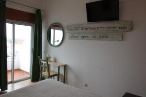 a bedroom with a bed and a mirror and a window at Guest House Oliveira in Boliqueime