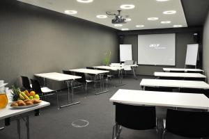 uma sala de aula com mesas e cadeiras brancas e um ecrã em Design Metropol Hotel Prague em Praga