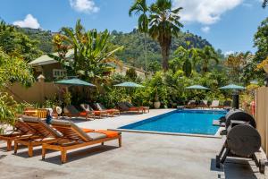 - une piscine avec des chaises longues et un complexe dans l'établissement Eden Hills Residence, à Anse Boileau