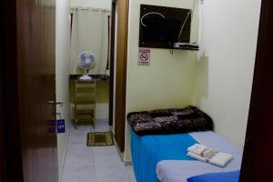 Habitación pequeña con cama y TV. en Hotel Guarany, en Canoinhas