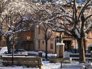 einen schneebedeckten Hof mit Bäumen und einem Gebäude in der Unterkunft Hostal La Cuineta de Cal Triuet in Gósol