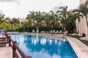 a swimming pool in a resort with palm trees at Coral Maya Stay Suites in Puerto Aventuras