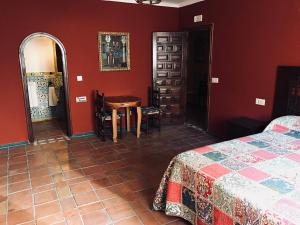 - une chambre avec des murs rouges, une table et un lit dans l'établissement Carmen De La Candelaria, à Grenade