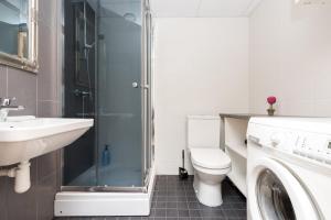 a bathroom with a toilet and a sink and a washing machine at Telliskivi apartment 16 in Tallinn