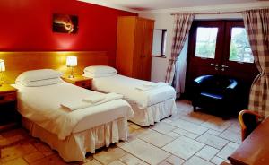 two beds in a room with red walls at King's Head Inn in Llangennith