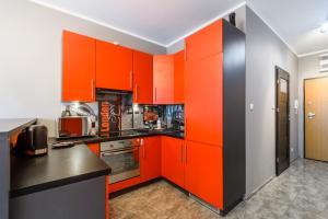 pomarańczowa kuchnia z czarnymi blatami i pomarańczowymi szafkami w obiekcie P&O Serviced Apartments GOCLAW w Warszawie