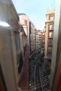 a train traveling through a city with tall buildings at Hostal Victoria in Málaga