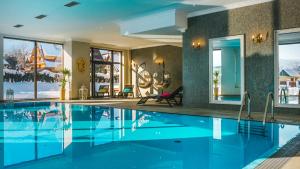 a swimming pool with blue water in a house at Hotel Paryski Art & Business Zakopane - Basen Jacuzzi Sauna Małpi Gaj in Zakopane