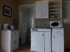 a kitchen with white cabinets and a microwave at Motel Cap Blanc in Kamouraska