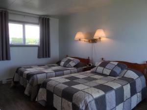 a bedroom with two beds and a window at Motel Cap Blanc in Kamouraska