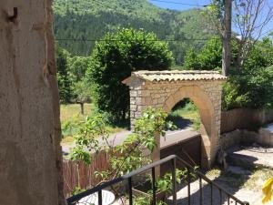 un arco de piedra en un jardín con una valla en Mas de la Pauze, en Reilhanette