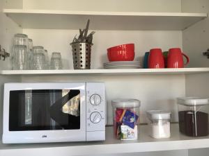a white microwave on a shelf with bowls and plates at B&B Canal Sight in Amsterdam
