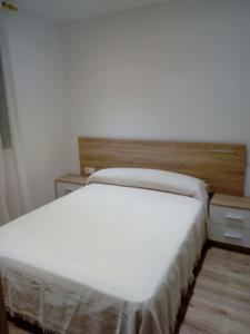 a bedroom with a white bed and two night stands at Alojamiento Samumari in Ciudad-Rodrigo