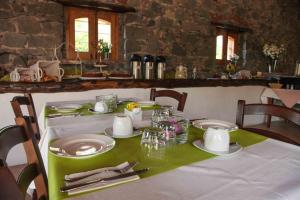 une table avec un tissu de table vert, des assiettes et de l'argenterie dans l'établissement Galea Farm House, à Riposto