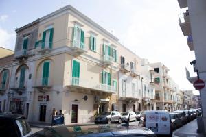 a building with green shutters and cars parked on a street at Dimora Iride in Monopoli
