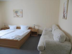 a bedroom with two beds and a couch in it at Hotel Merkur Garni in Sarstedt