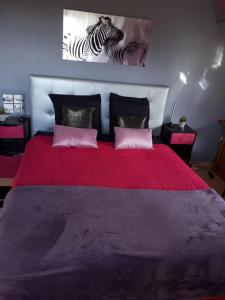 a bedroom with a red bed with two zebras on the wall at La mare aux chevres in Reux