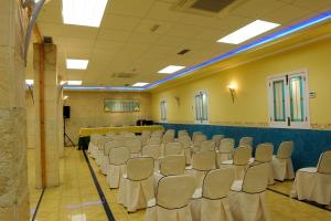 una sala de conferencias con sillas blancas y un escenario en Hotel Corregidor, en Segovia
