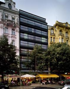 un edificio alto con mesas y sombrillas en una ciudad en Design Metropol Hotel Prague en Praga