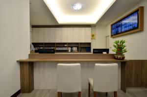 a lobby with a bar with three white chairs at Hoya Resort Hotel Chiayi in Minxiong
