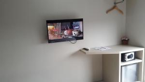 une télévision suspendue sur un mur avec une table dans l'établissement Wanadu Residence, à Tangerang