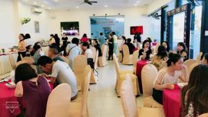 a group of people sitting at tables in a restaurant at Bamboo Green Riverside Hotel in Danang