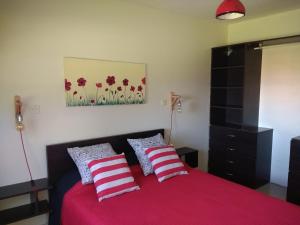 a bedroom with a red bed with two red and white pillows at Cabaña Buccia in Mar del Plata