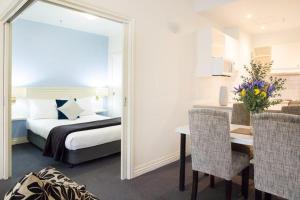 1 dormitorio con cama, mesa y espejo en Hotel Collins en Melbourne
