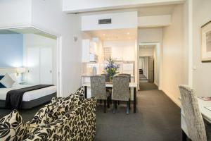 une chambre d'hôtel avec un lit, une table et des chaises dans l'établissement Hotel Collins, à Melbourne