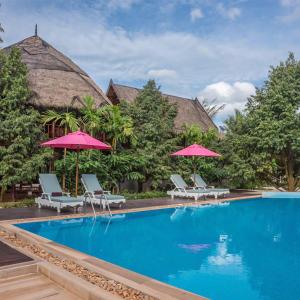 uma piscina de resort com cadeiras e guarda-sóis em Orchard Pa La U em Ban Pa Lau