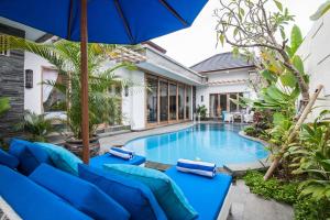 een zwembad met blauwe stoelen en een parasol bij Ambermoon Villa 2 in Seminyak