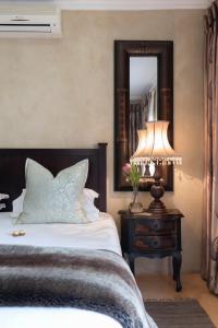 1 dormitorio con cama, lámpara y espejo en Our Heritage Guesthouse en Kempton Park