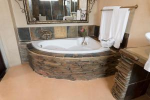 Our Heritage Guesthouse في كيمبتون بارك: حمام مع حوض استحمام مصنوع من الطوب