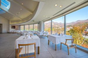 a dining room with tables and chairs and windows at Takamiya Hotel Rurikura Resort in Zao Onsen