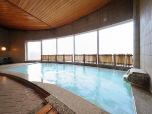 a large swimming pool in a building with windows at Takamiya Hotel Rurikura Resort in Zao Onsen