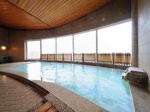 a large swimming pool in a building with windows at Takamiya Hotel Rurikura Resort in Zaō Onsen