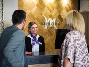 a woman standing at a counter talking to two people at Mercure Doncaster Centre Danum Hotel in Doncaster