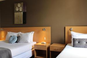 a hotel room with two beds with white pillows at El Toro Motor Inn in Warwick Farm