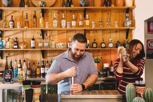 a man and a woman standing behind a bar making a drink at El Toro Motor Inn in Warwick Farm