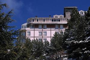 Un edificio alto y blanco con árboles delante. en Hotel Reino Nevado, en Sierra Nevada
