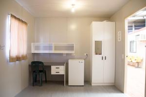 een keuken met een witte koelkast en een tafel bij STORK RD BUDGET ROOMS - PRIVATE ROOMS WITH SHARED BATHROOMS access to POOL in Longreach