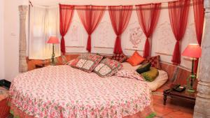 a bedroom with a large bed with red curtains at Dera Mandawa in Jaipur