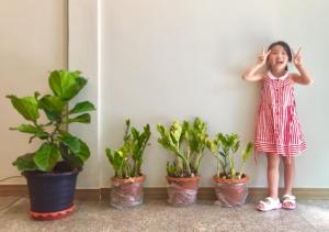 曼谷的住宿－My Home N1 - BTS Ratchathewi，站在四个盆栽植物旁的小女孩