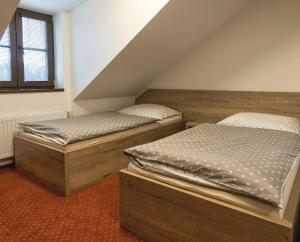 2 łóżka pojedyncze w pokoju na poddaszu w obiekcie Panský mlýn w Opawie